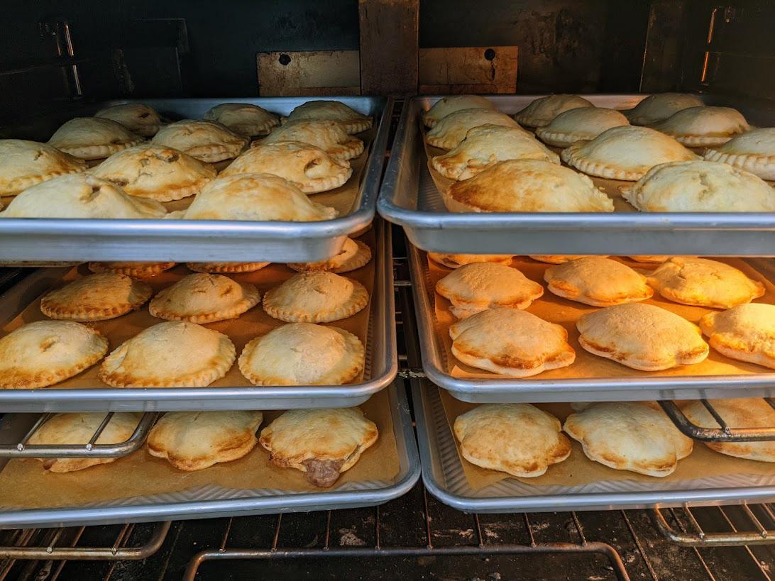 Various empanolis on baking sheets in an oven