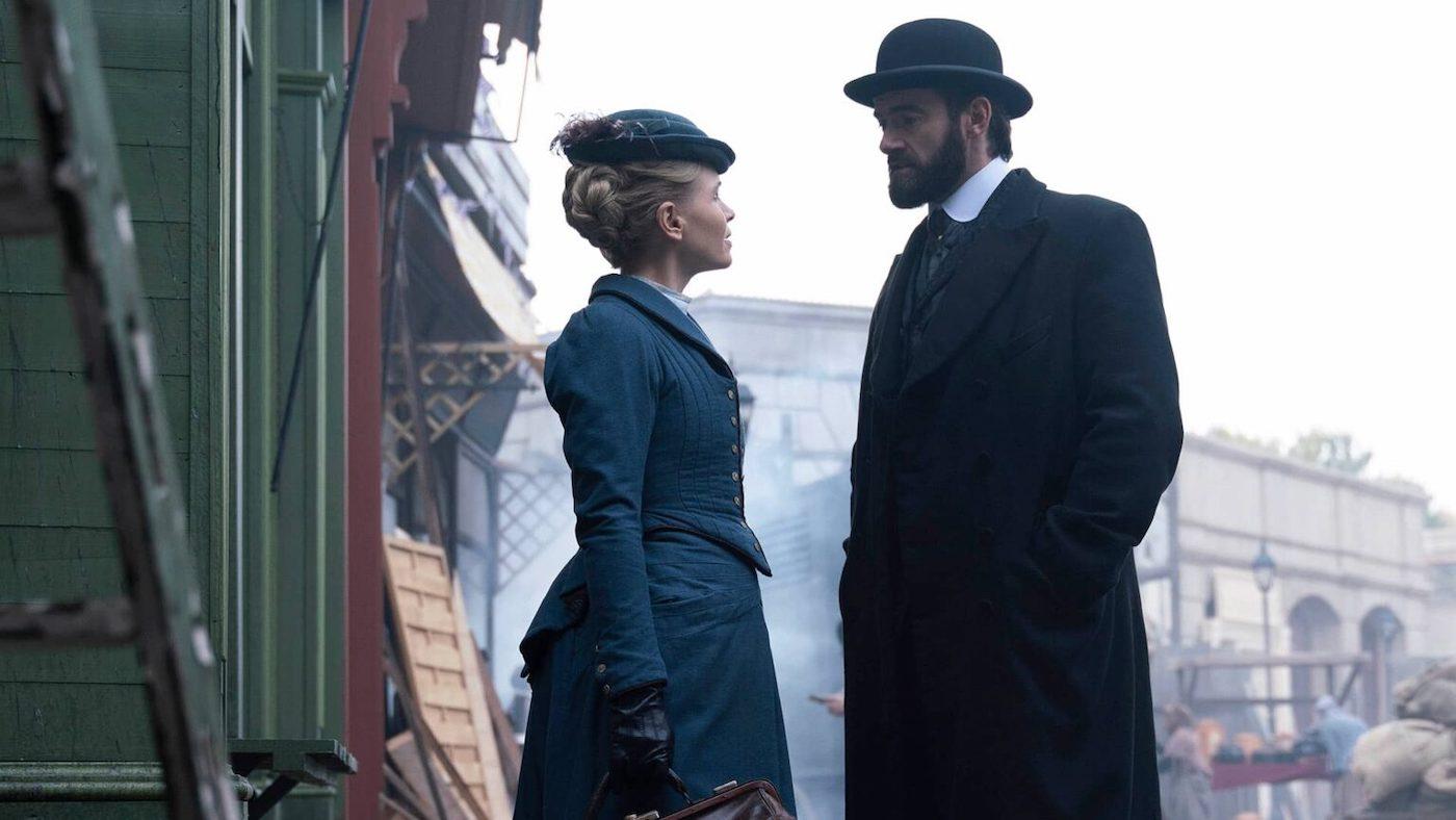 Eliza and William stand in the street and look at each other