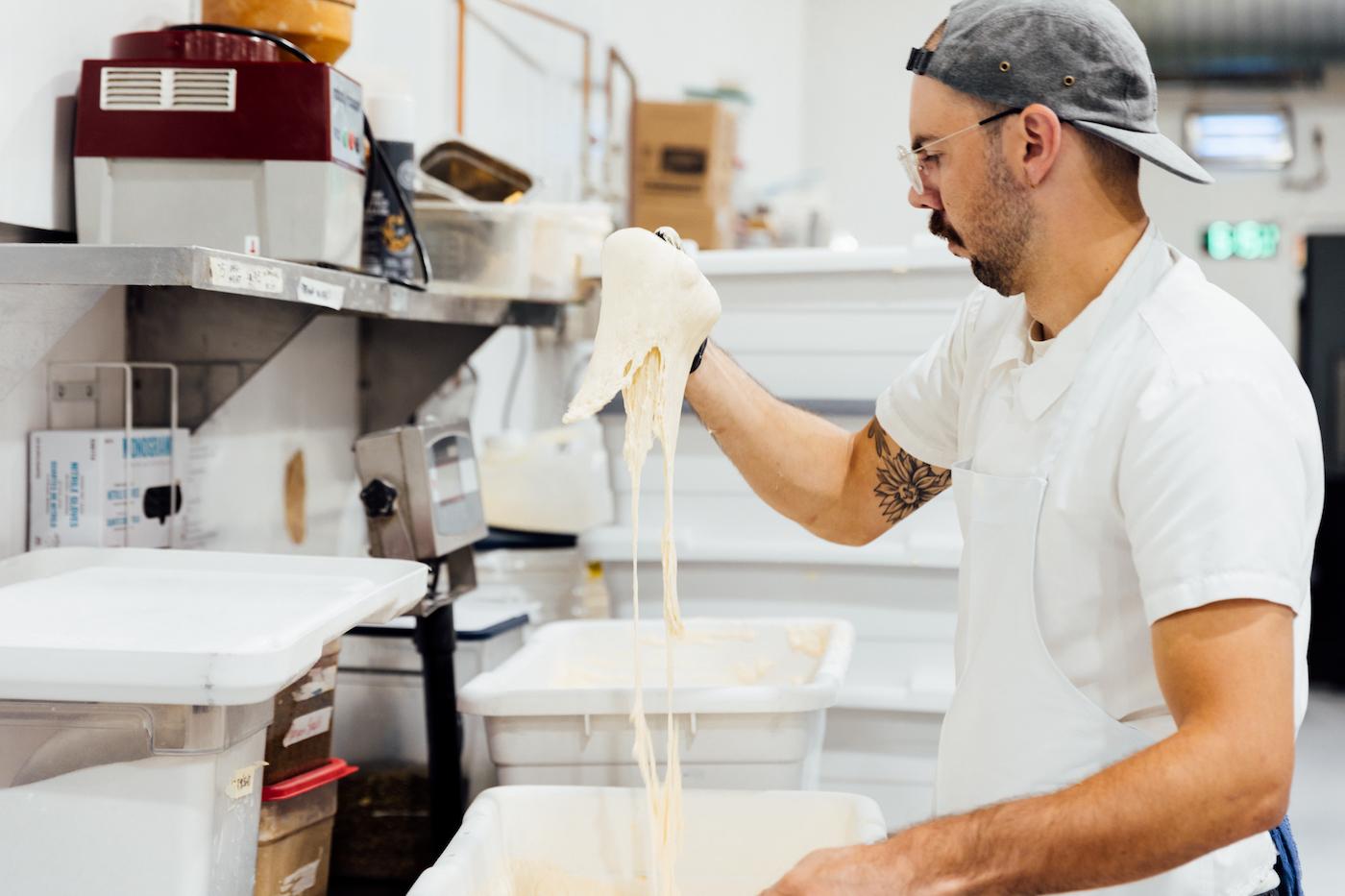 Mickey Dennis lifts some sticky bread dough out of a container