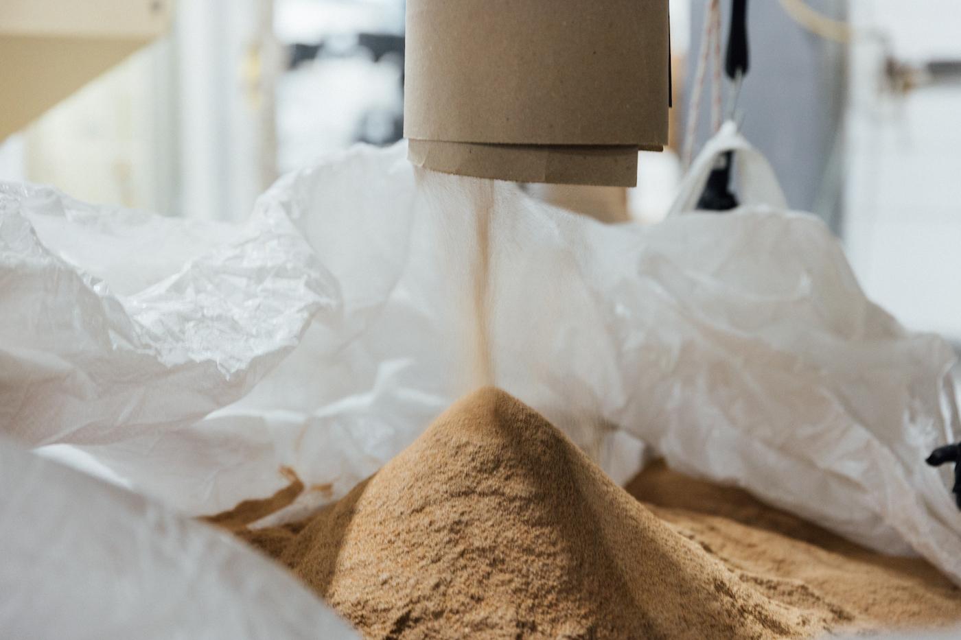 Flour pours into a bag after being milled