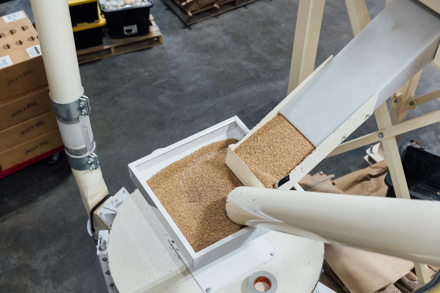 Grain pours into the top of a stone mill