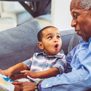 Toddler reading with gramps.