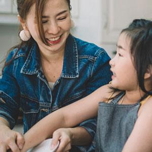 Mom and child washing dishes together.