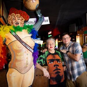 The owners of Big Chicks pose next to a figure with a rainbow boa