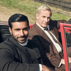 Alphy and Geordie sit in an open-top red convertible