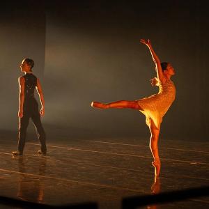 A ballerina on stage with another dancer facing away