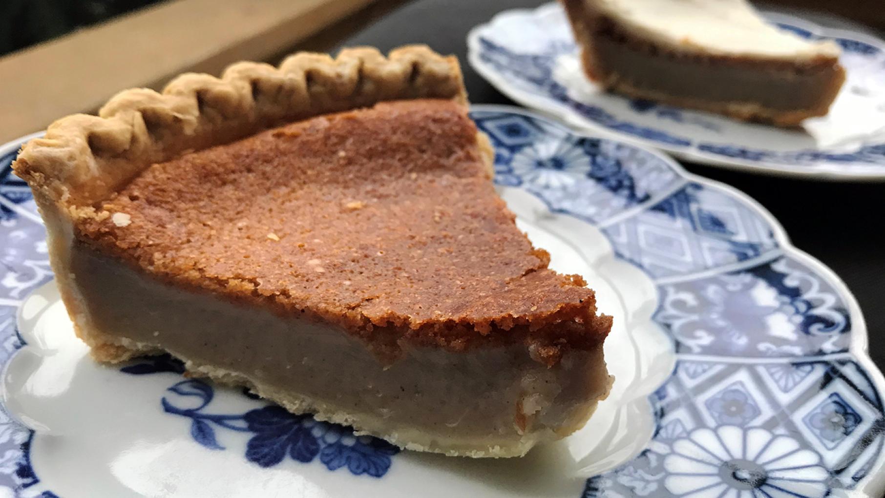 A slice of Imani's Original bean pie, with a cream cheese-frosted slice in the background A slice of Imani's Original bean pie, with a cream cheese-frosted slice in the background