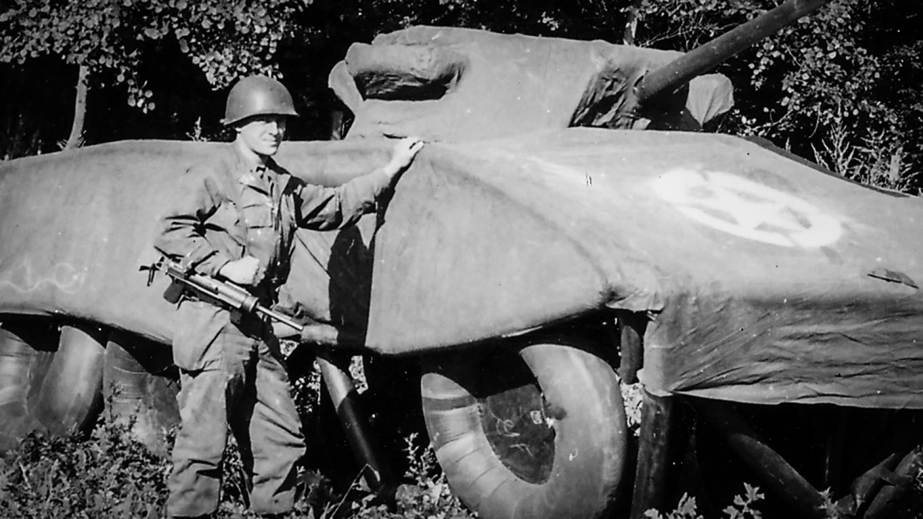 A soldier stands next to a dummy M8 Greyhound armored car. Credit: National Archives / Illinois Holocaust Museum A soldier standing with a phony armored vehicle