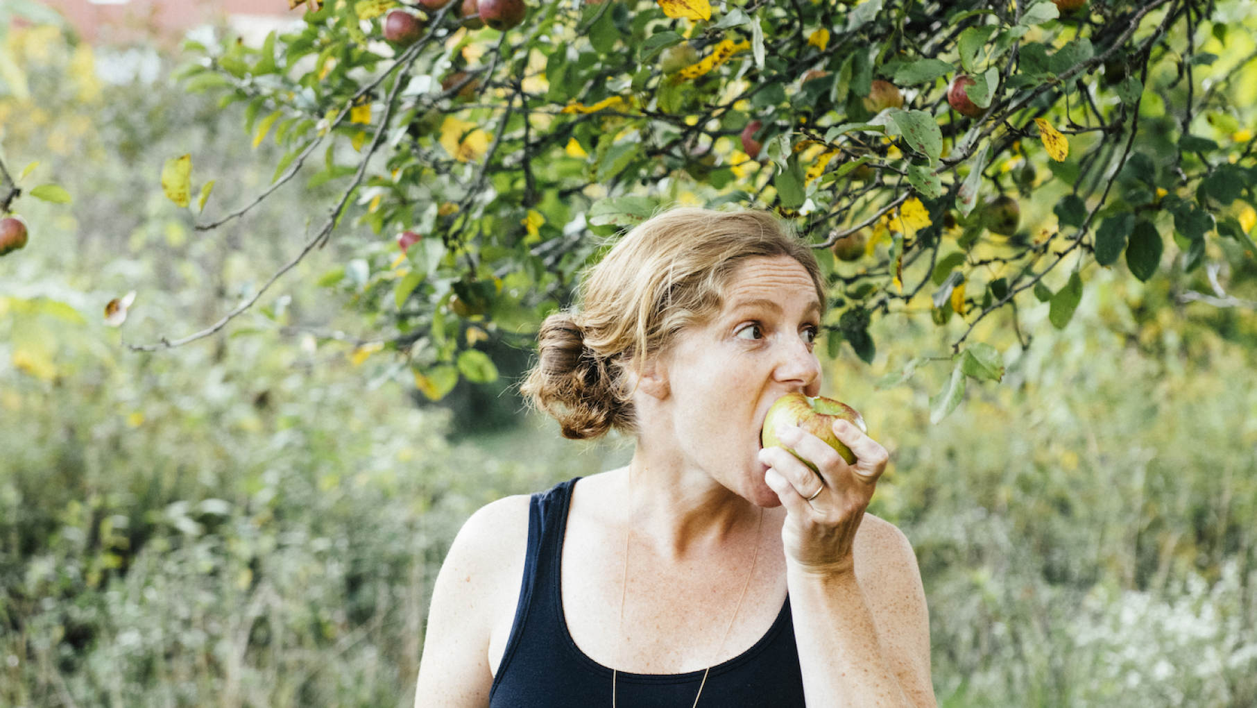“Fewer and fewer people just don’t know farmers, and so they don’t understand what goes into it,” says chef and cookbook author Abra Berens. Photo: E.E. Berger Abra Berens biting an apple under an apple tree