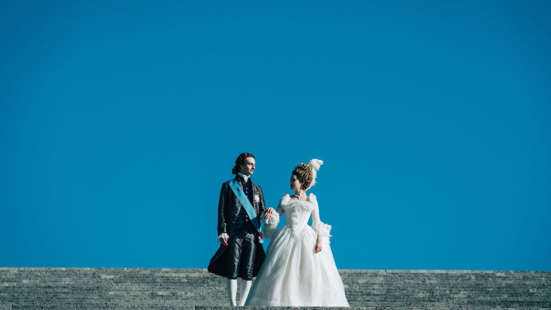 Louis Auguste and Marie Antoinette stand against a blue sky