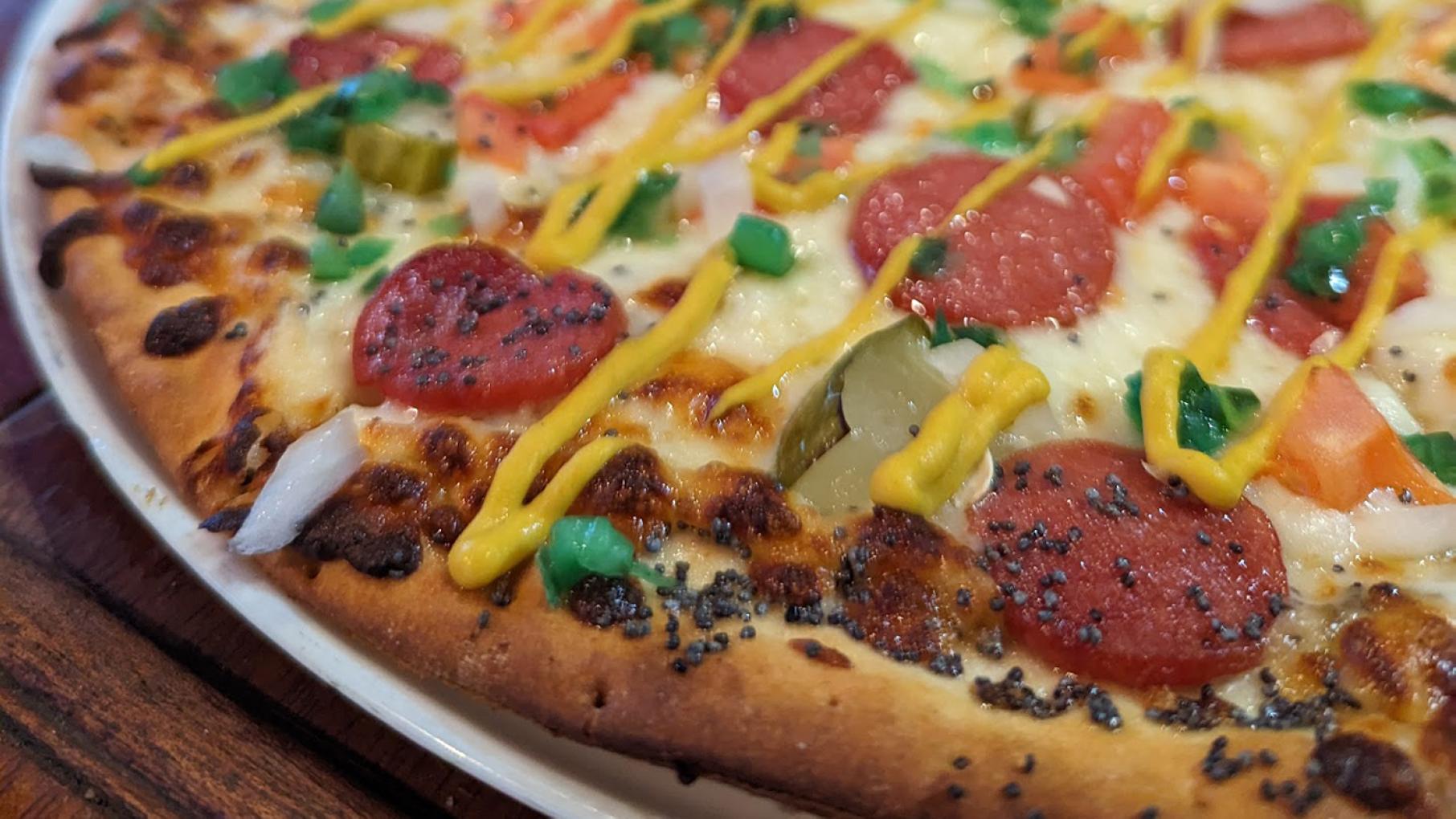 The Olympic Tavern in Rockford is currently serving a Chicago Hot Dog pizza. Photo: Courtesy Zak Rotello A Chicago Dog Pizza from the Olympic Tavern in Rockford, with a poppy seed and celery salt crust, sliced hot dogs, pickles, tomato, onion, giardiniera, yellow mustard, and relish