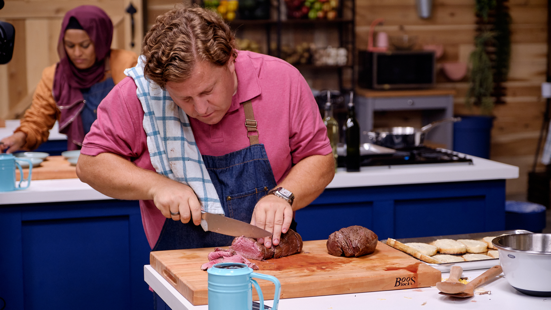 Ted Pappas slices meat on a cutting board on The Great American Recipe