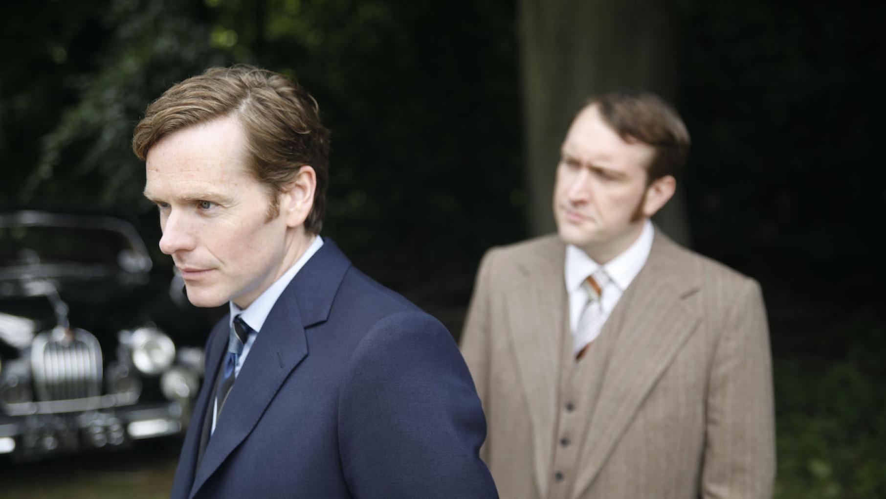 Endeavour Morse and Jim Strange stand in front of a car looking into the distance