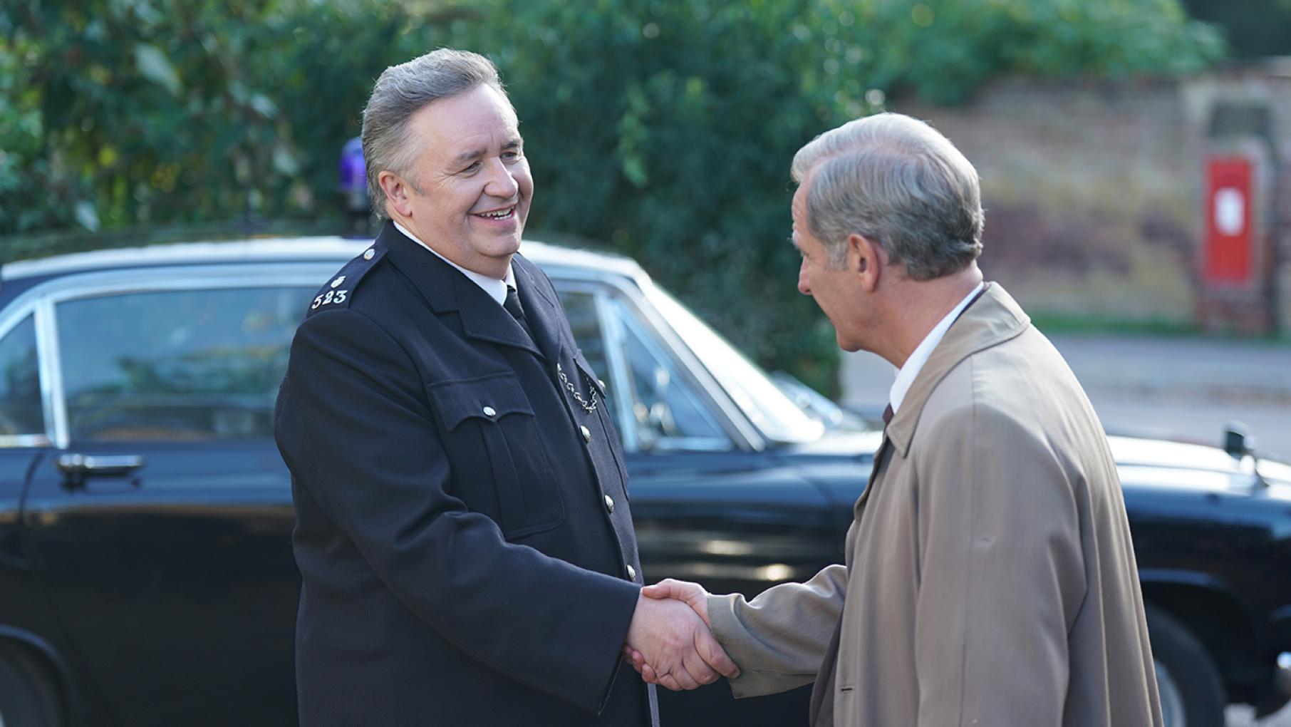 PC MacKenzie shakes Geordie's hand in front of a car