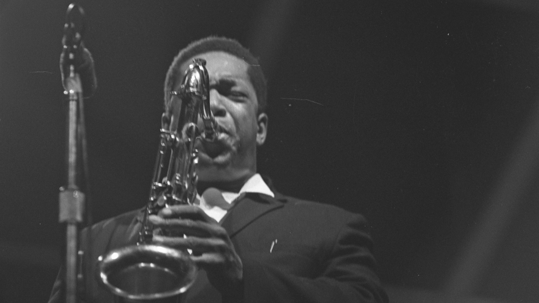 John Coltrane was one of several superstars to perform at the 'DownBeat' jazz festival at Soldier Field in 1965. Photo: Chicago History Museum, ICHi-100398; Raeburn Flerlage, photographer John Coltrane plays saxophone in front of a mic with a black background in 1965