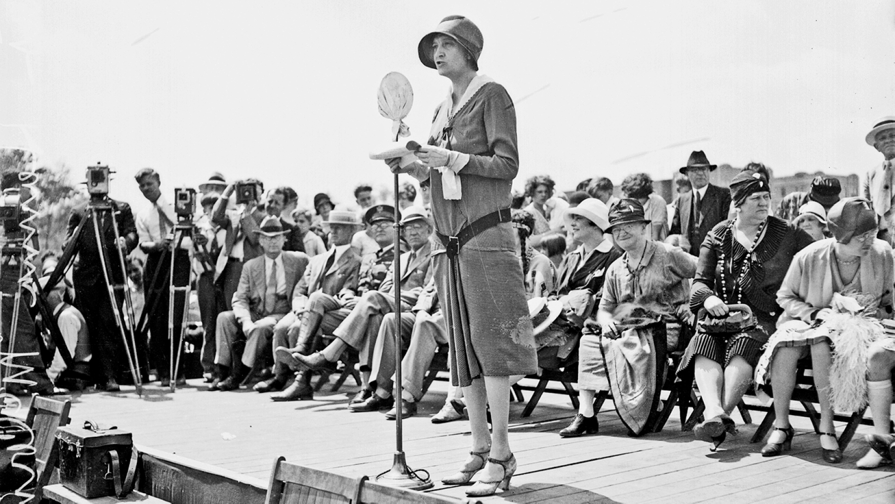 Politician Ruth Hanna McCormick, U.S. Representative from Illinois at-large from 1929-1931, standing on an outdoor stage in Chicago, Illinois, 1929. Cameramen standing behind cameras mounted on tripods are visible in the background.