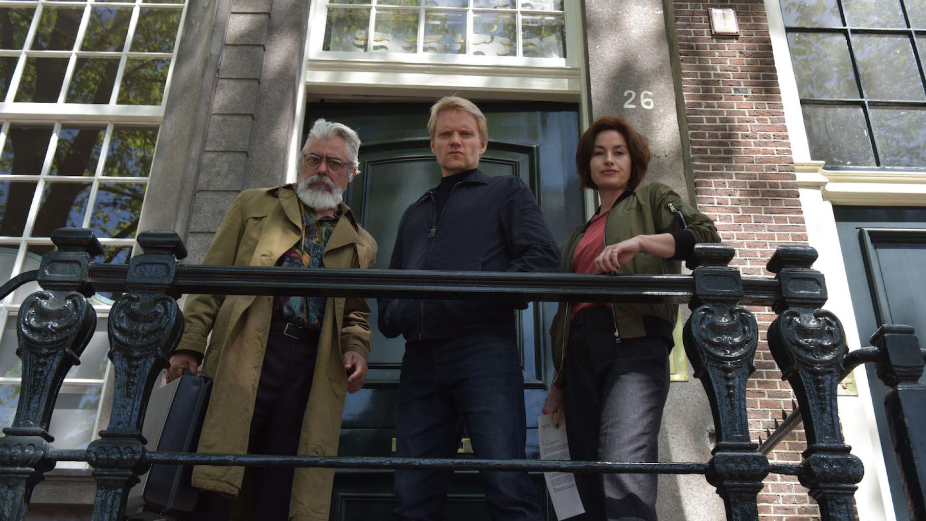 The team investigates the murder of a museum curator by a possibly antique sword. Credit: Company Pictures, NL Films & A3MI Hendrik, Van der Valk, and Lucienne look over a railing