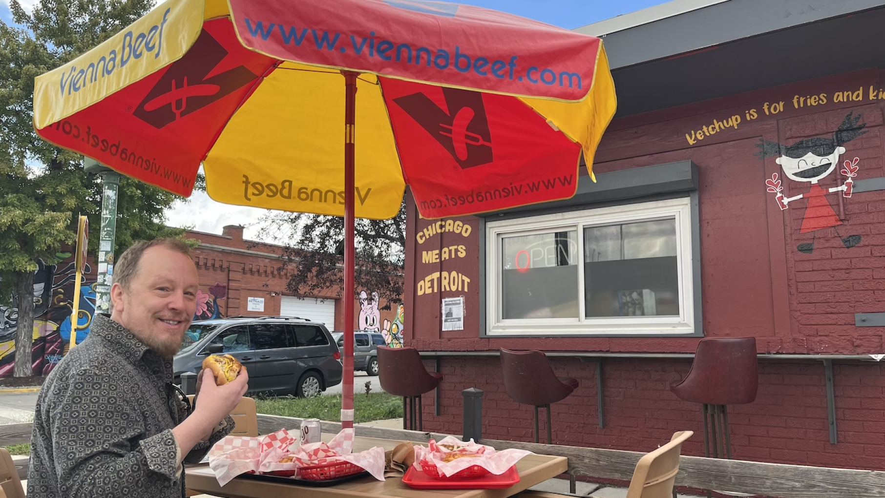Paul Fehribach celebrates regional specialties like the coney dog (enjoyed by him here at Lola's Coney Island) in his new book, 'Midwestern Cuisine' Paul Fehribach sits at an outdoor table in front of Lola's Coney Island under an umbrella, holding a coney dog