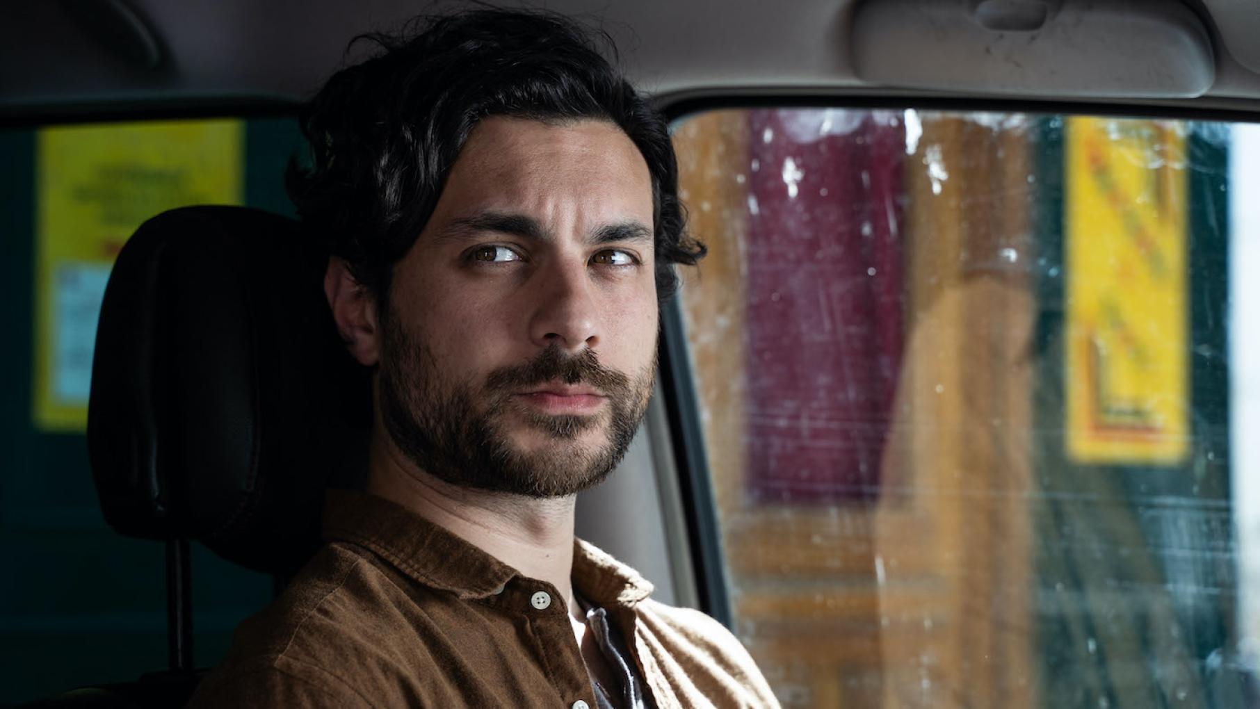 The appearance of the police to question Karol comes at a horrible time for him. Credit: Mainstreet Productions Karol sits in a van and looks out the window
