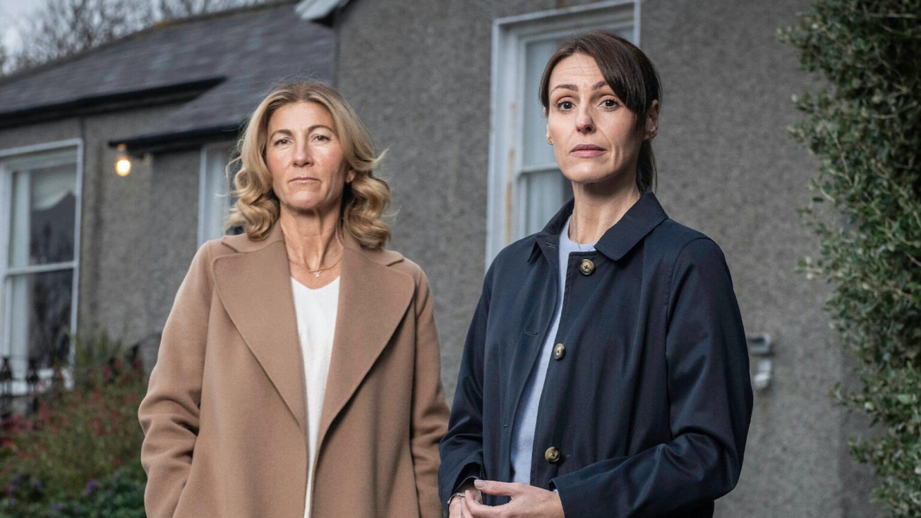 Rosaline and Becca stand in coats outside a house