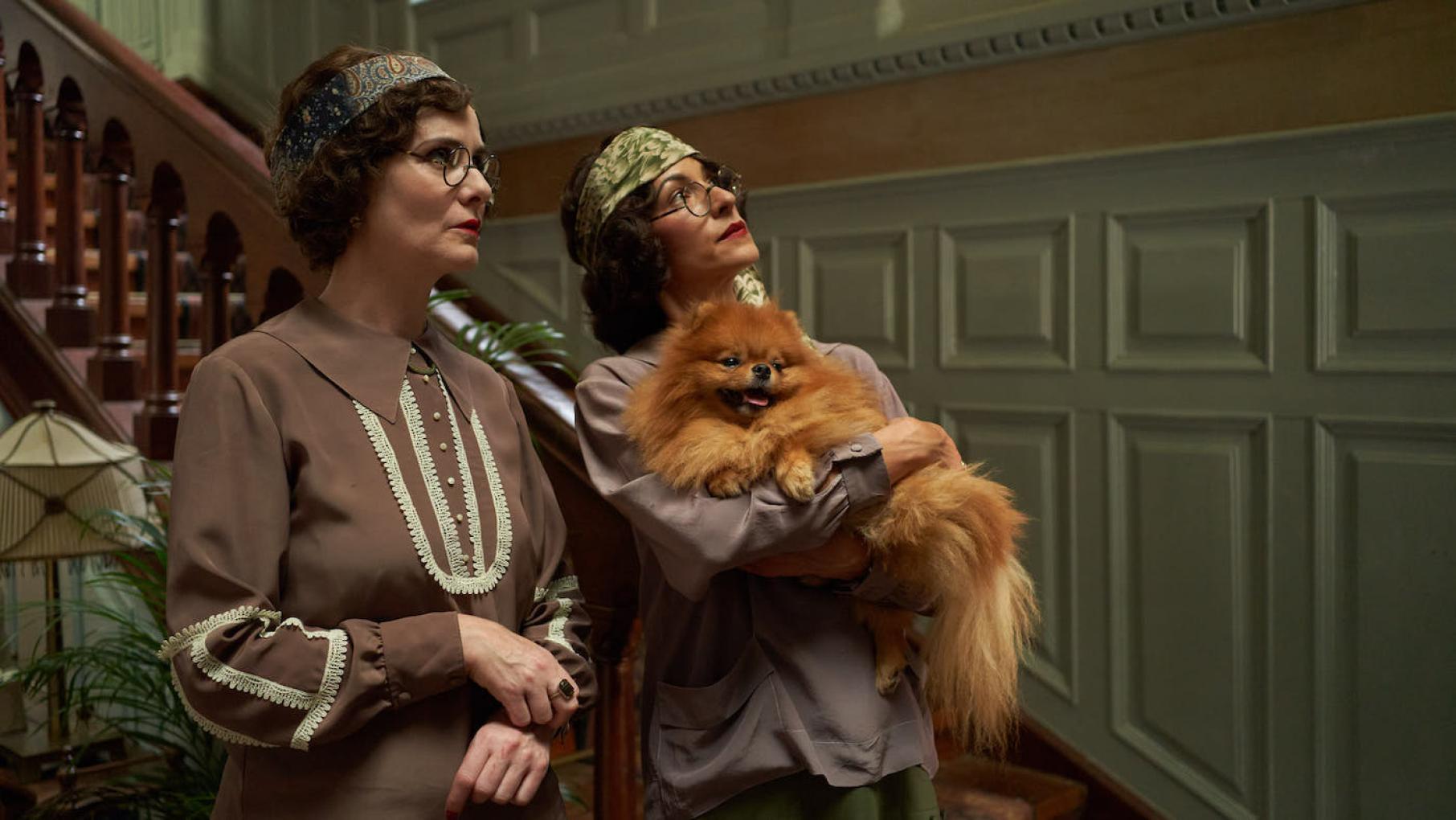 Every guest could be a travel inspector, so even terrors like the Dodsworth sisters merit stellar treatment. Credit: Eagle Eye Drama Two women in flapper dress and glasses look up while one holds a Pomeranian dog