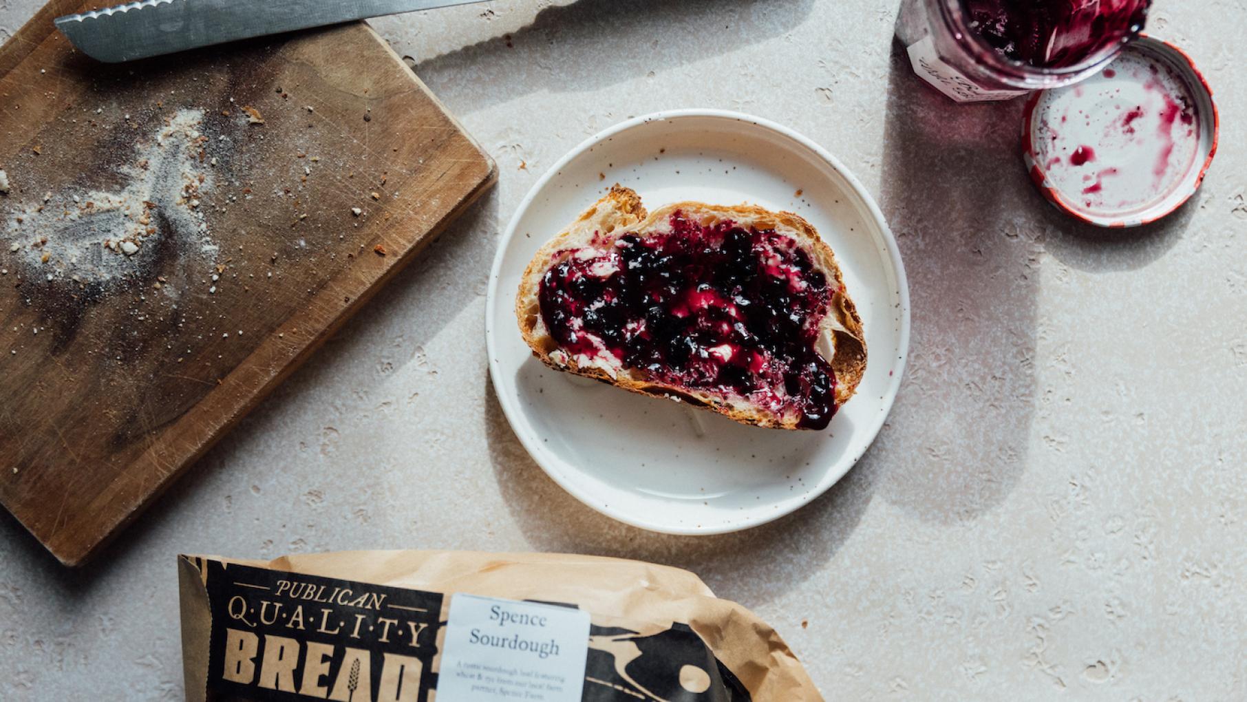 A loaf of bread ties you to a baker, a miller, and a farmer, even if the connection is obscured in the present day. Credit: Sandy Noto for WTTW A slice of toast covered with jam sits on a plate next to a cutting board