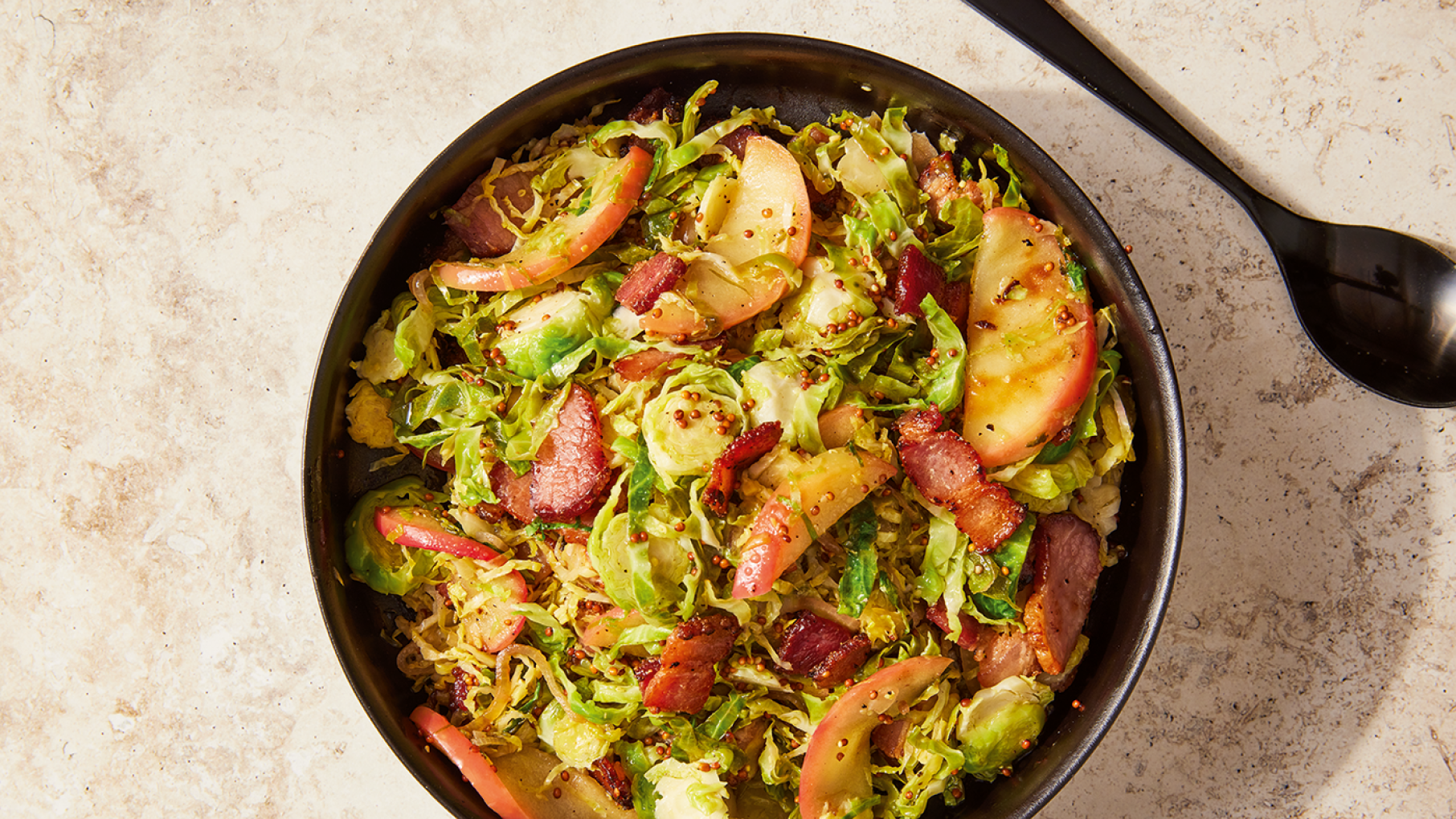 A simple vinaigrette enlivens Brussels sprouts in this easy recipe from 'Milk Street Simple.' Credit: Erik Bernstein for Milk Street Brussels Sprouts with apples and bacon in a black bowl