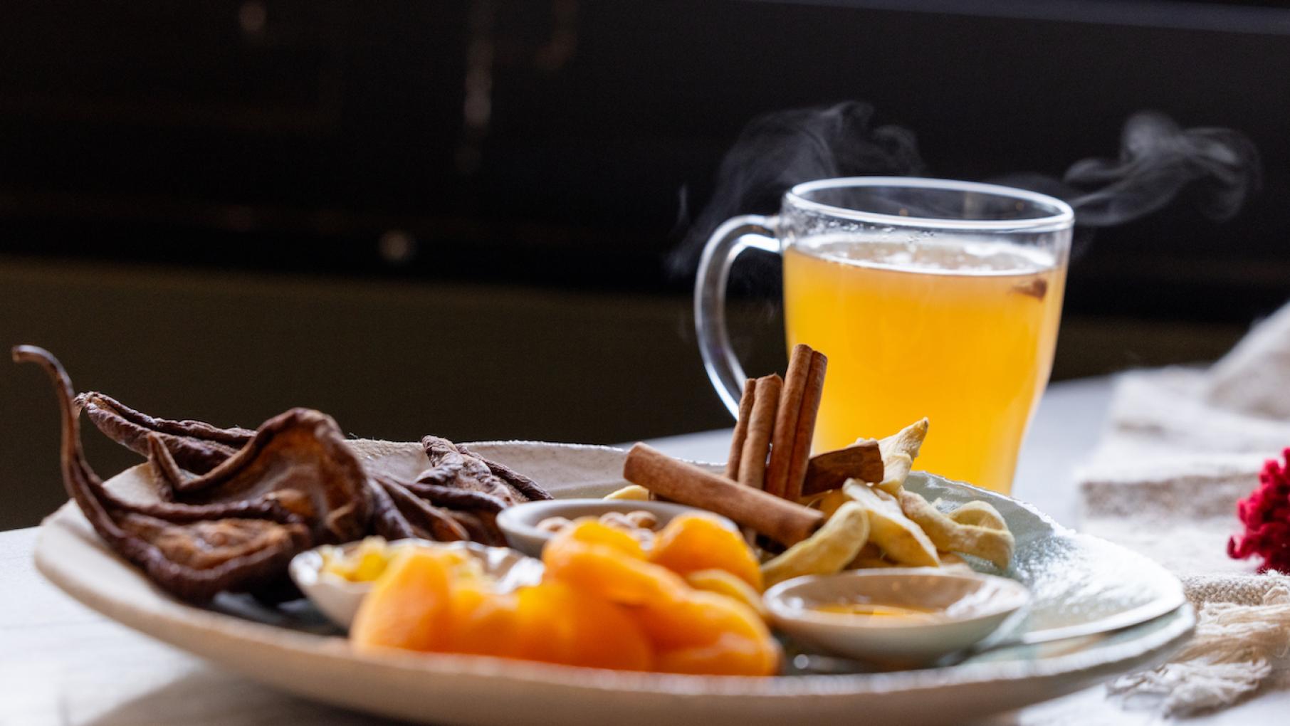 Uzvar is a Ukrainian cider of dried fruits, nuts, and spices. Credit: Kathleen Hinkel for WTTW A steaming mug of cider behind a plate of its ingredients