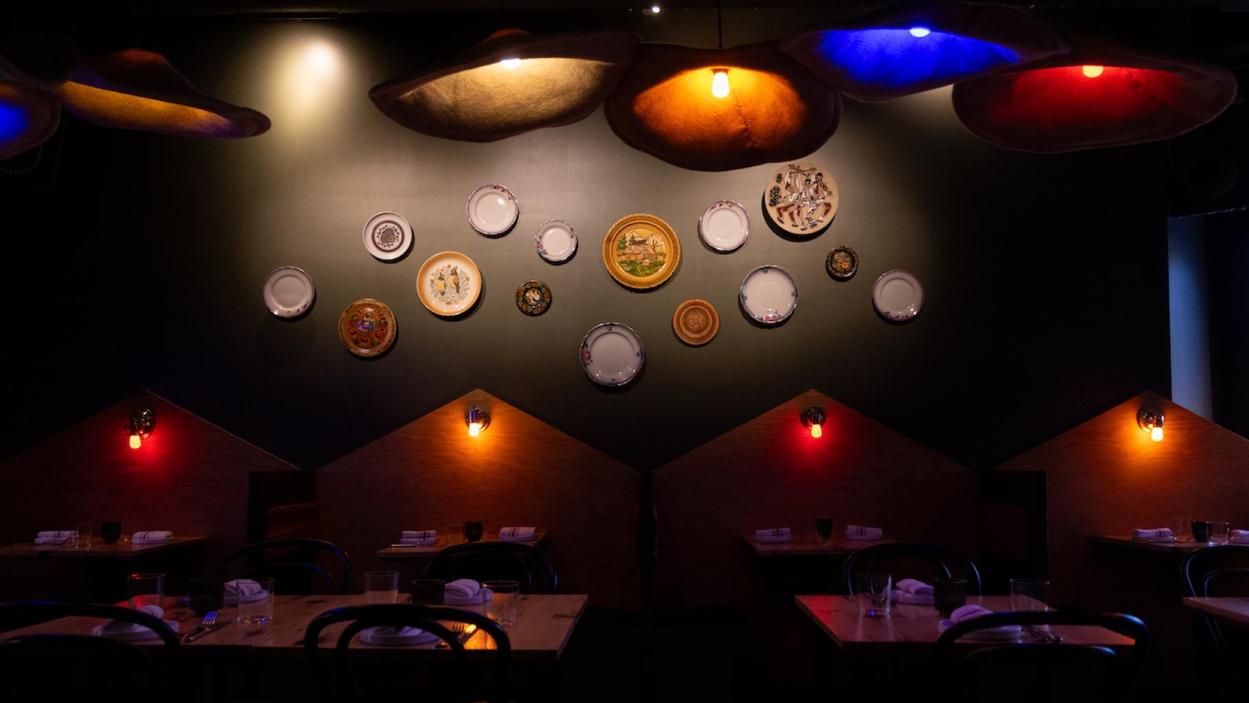 Johnny Clark wants to introduce people to Ukrainian food and culture at Anelya. Credit: Kathleen Hinkel for WTTW The dining room of Anelya, with decorative plates on a wall and darkly lit booths