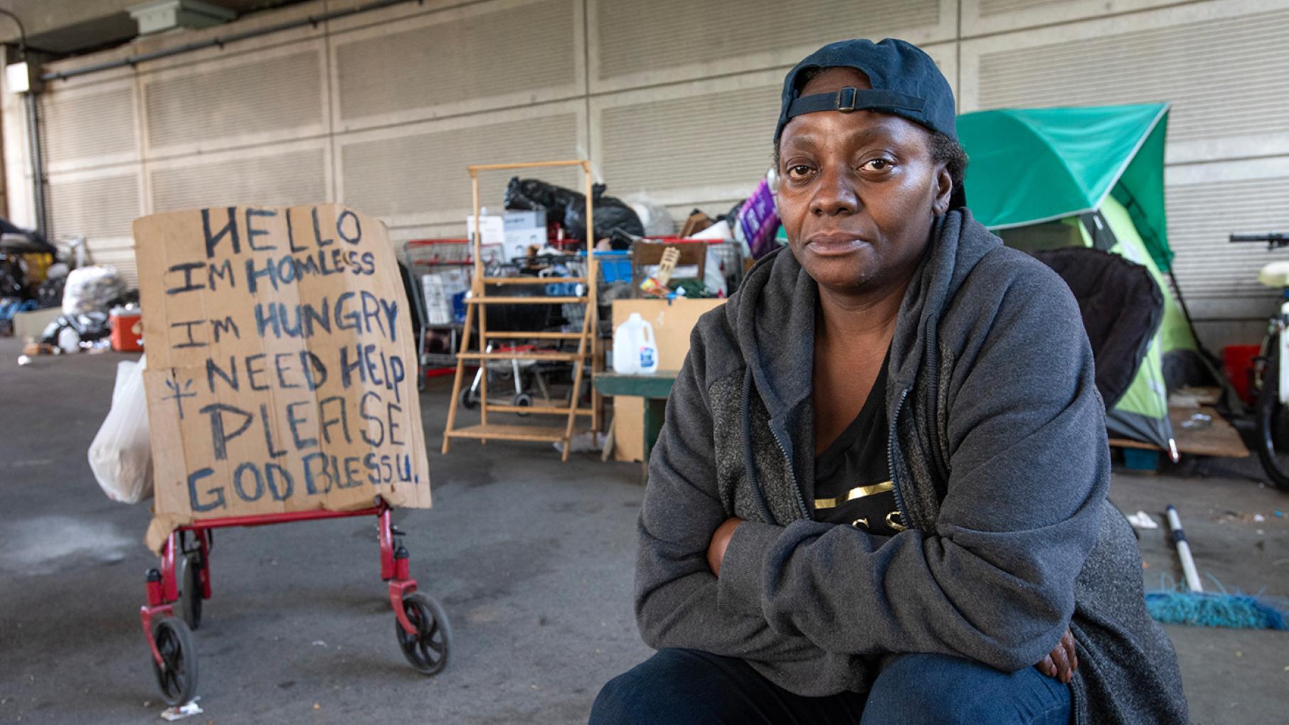 Yolanda is one of the subjects of 'FIRSTHAND: Homeless.' Credit: Lloyd DeGrane for WTTW Yolanda sits near her cardboard sign on a walker asking for help in front of an encampment of people experiencing homelessness