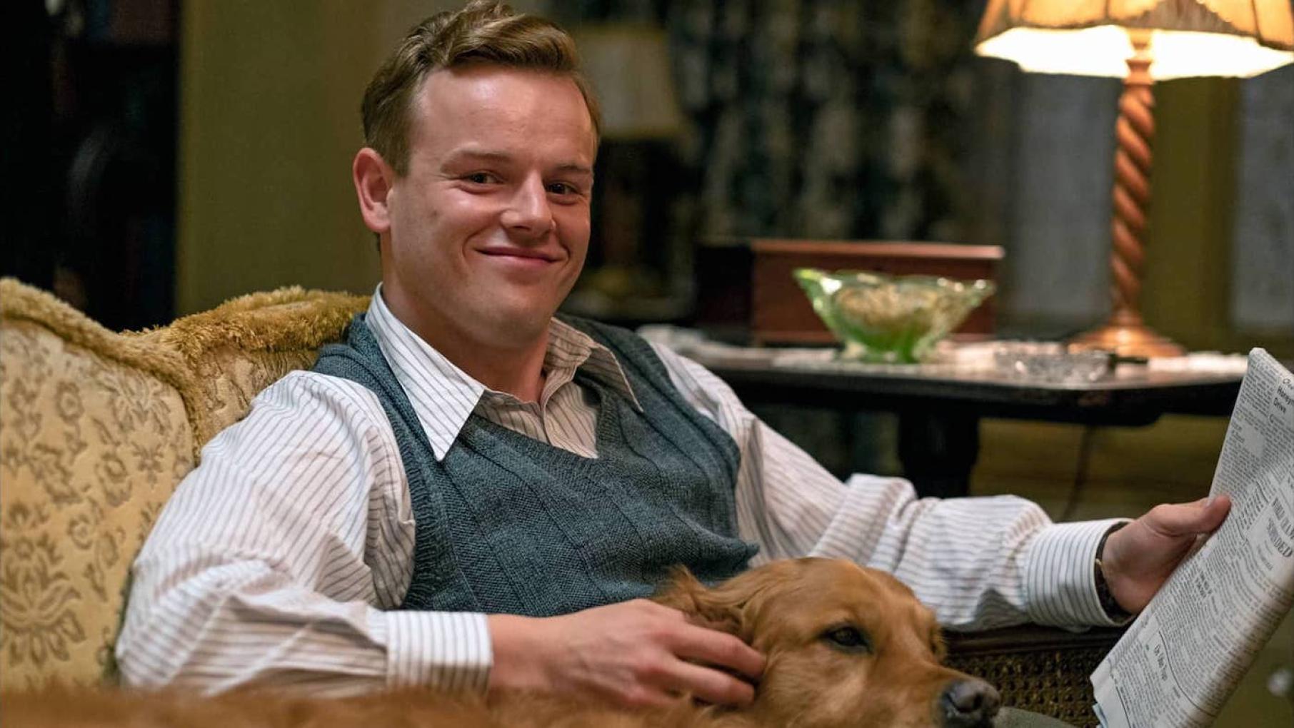 Tristan will return for another season of 'All Creatures Great and Small.' Credit: Playground Entertainment and Masterpiece Tristan sits in a chair with a dog and a newspaper and smiles