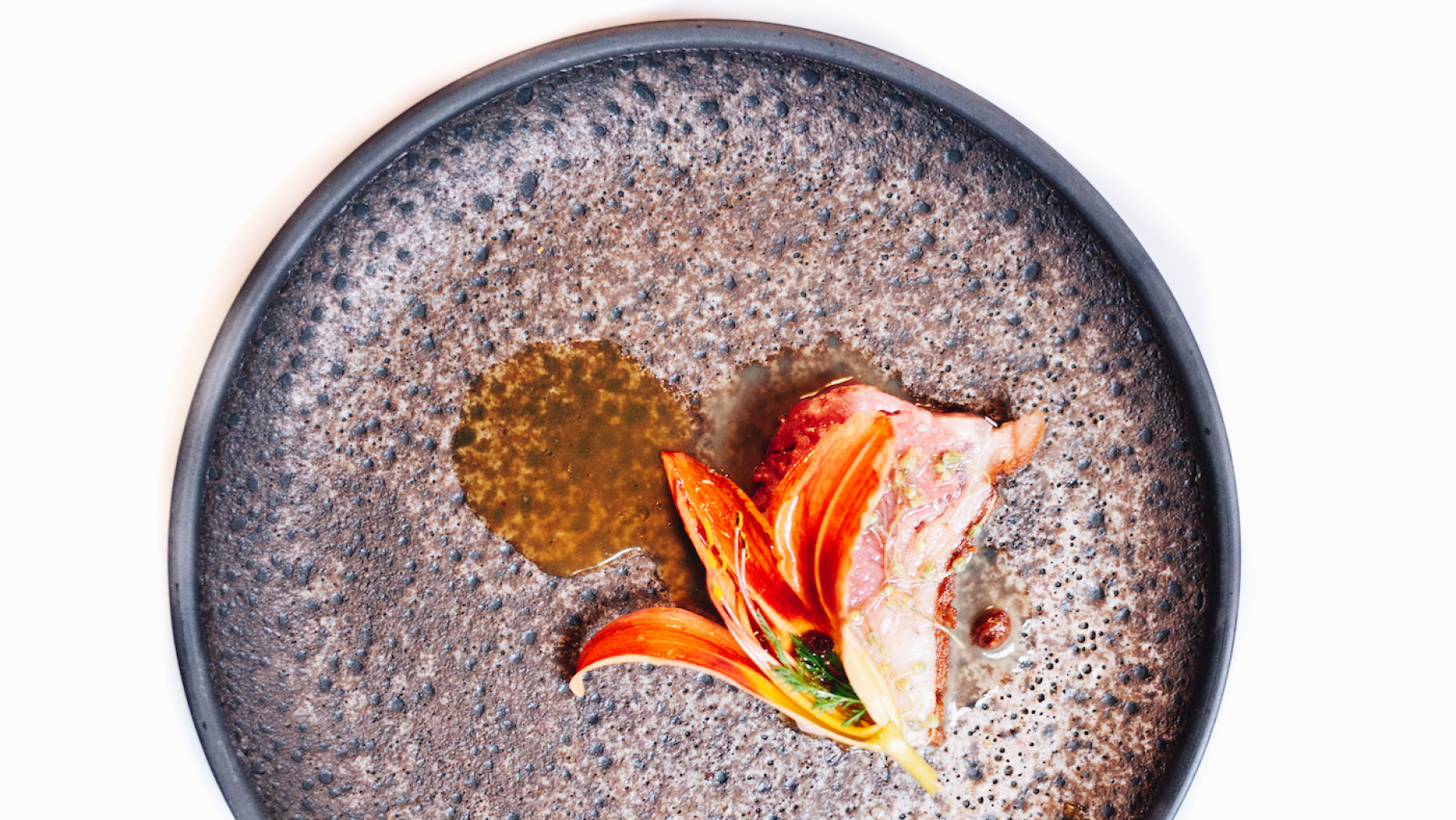 Chicago's Smyth is one of only thirteen restaurants in the United States with three Michelin stars. Credit: Courtesy Smyth A pebbled plate with an artfully plated dish featuring a flower and sauce