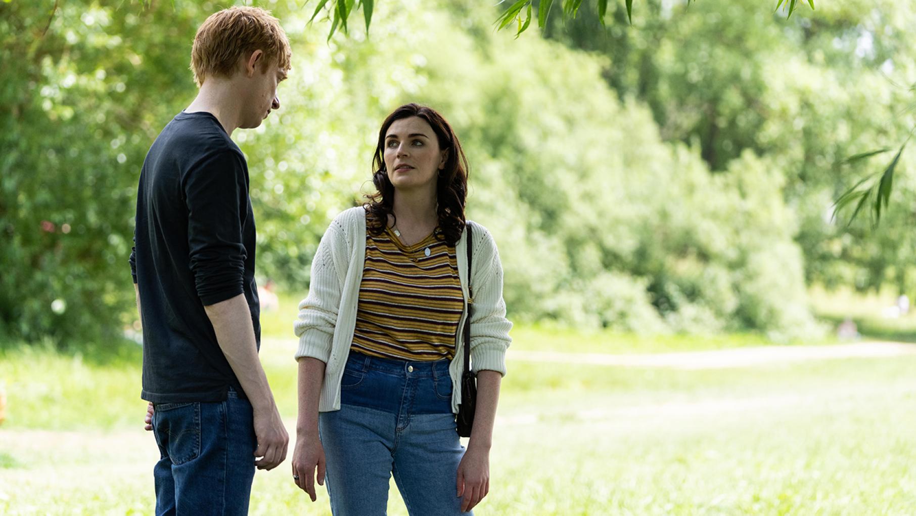 Jack stands and looks at Lynn under a tree