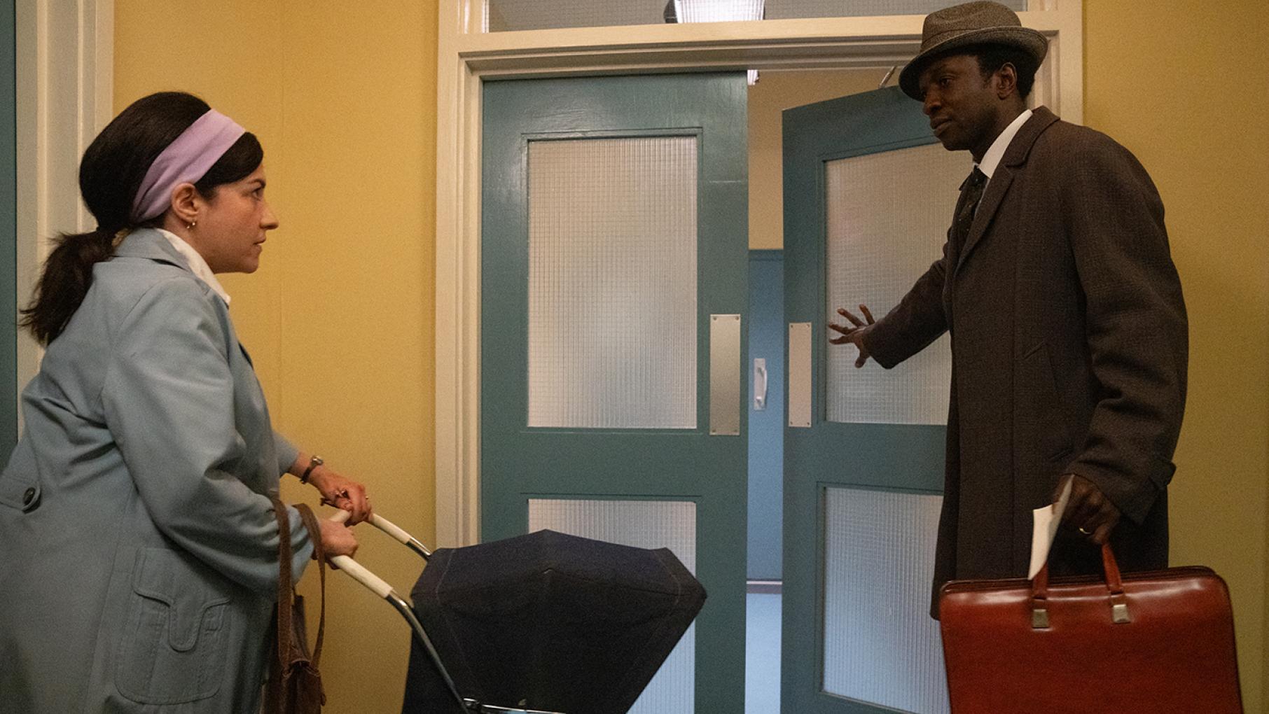 Cyril and the midwives help a woman whose husband has left her. Credit: Olly Courtly for BBC Studios and Neal Street Productions Cyril opens a door for a woman with a stroller