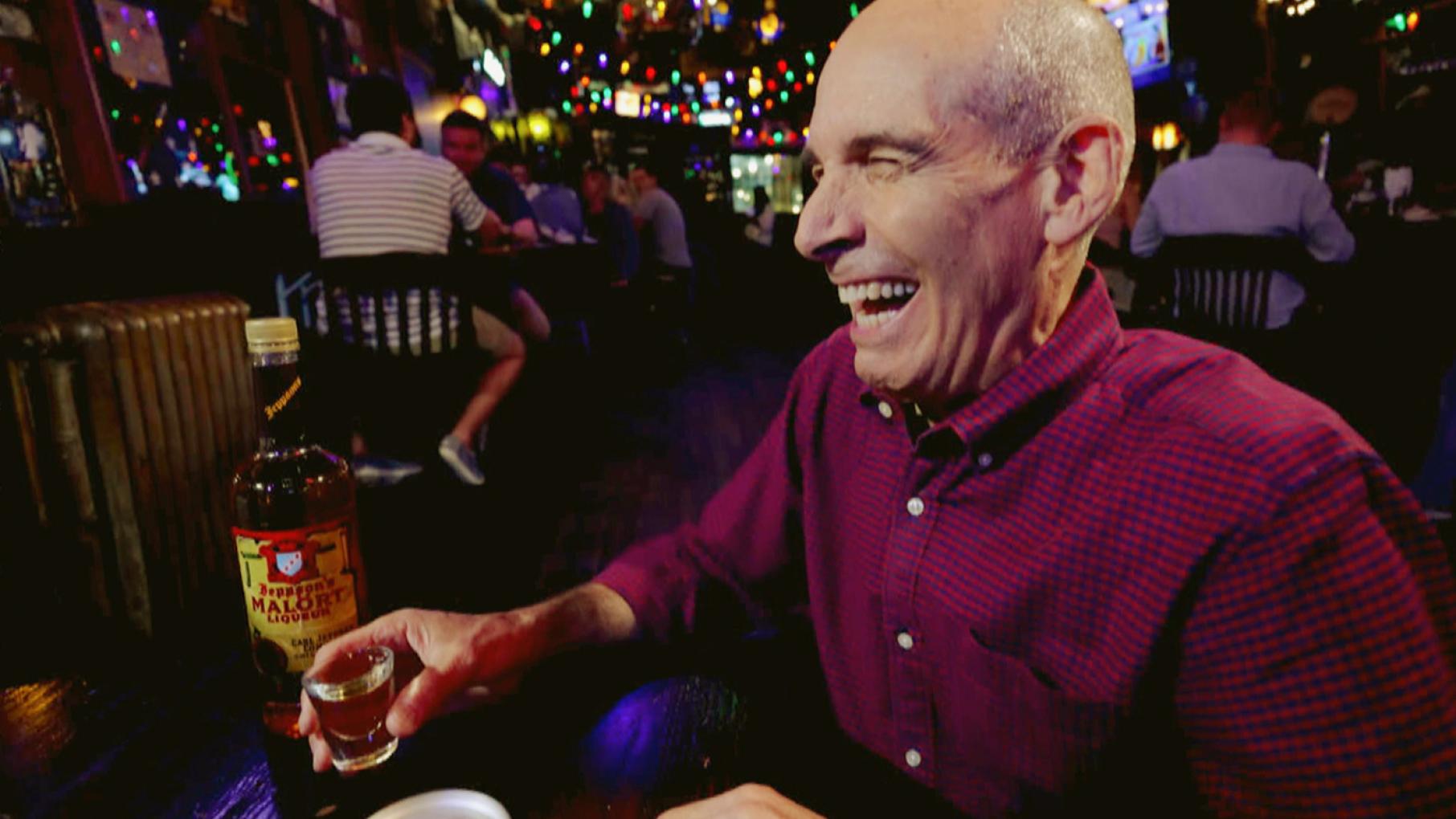 Geoffrey Baer makes a face while holding a shot glass of Malört.