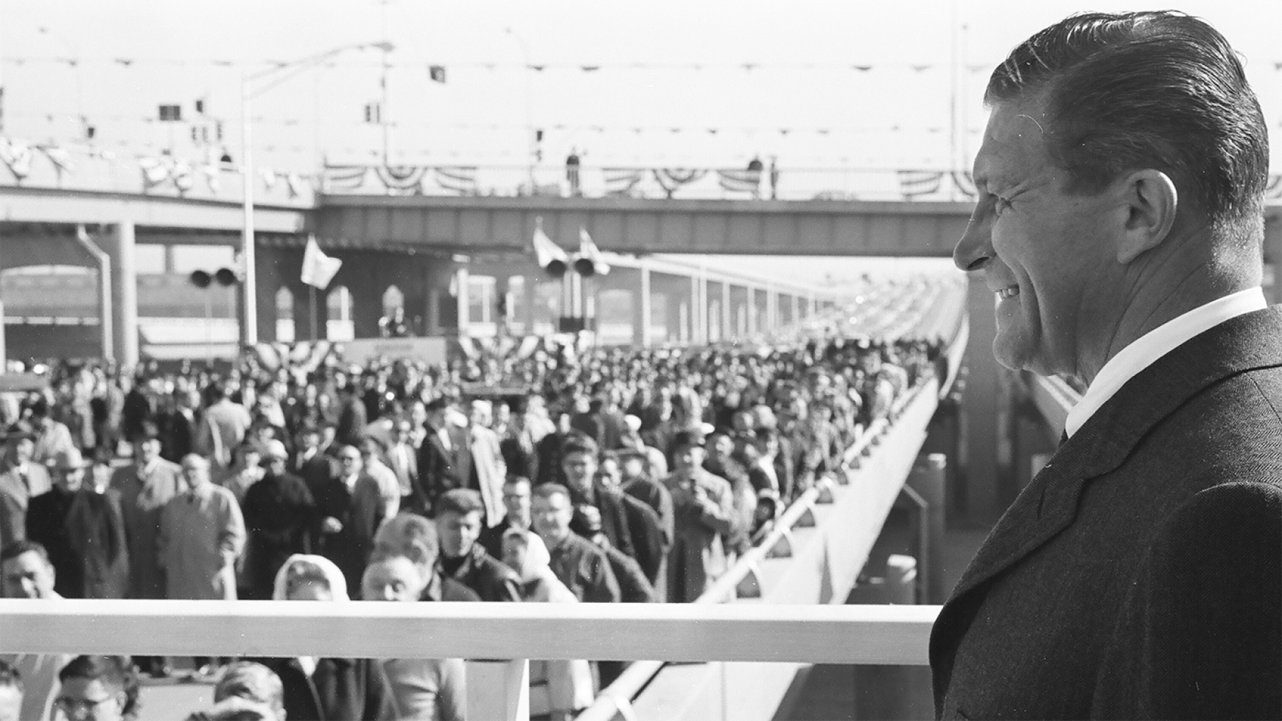 Otto Kerner smiles in front of a crowd of people on a new highway in a black and white photo