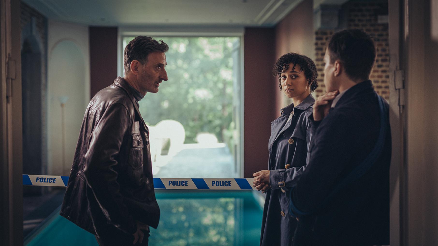 A bride is found drowned in a pool the morning after her wedding. Credit: Sofie Gheysens/Eagle Eye Drama Rabbit, Lisa, and Dan stand in front of an indoor pool