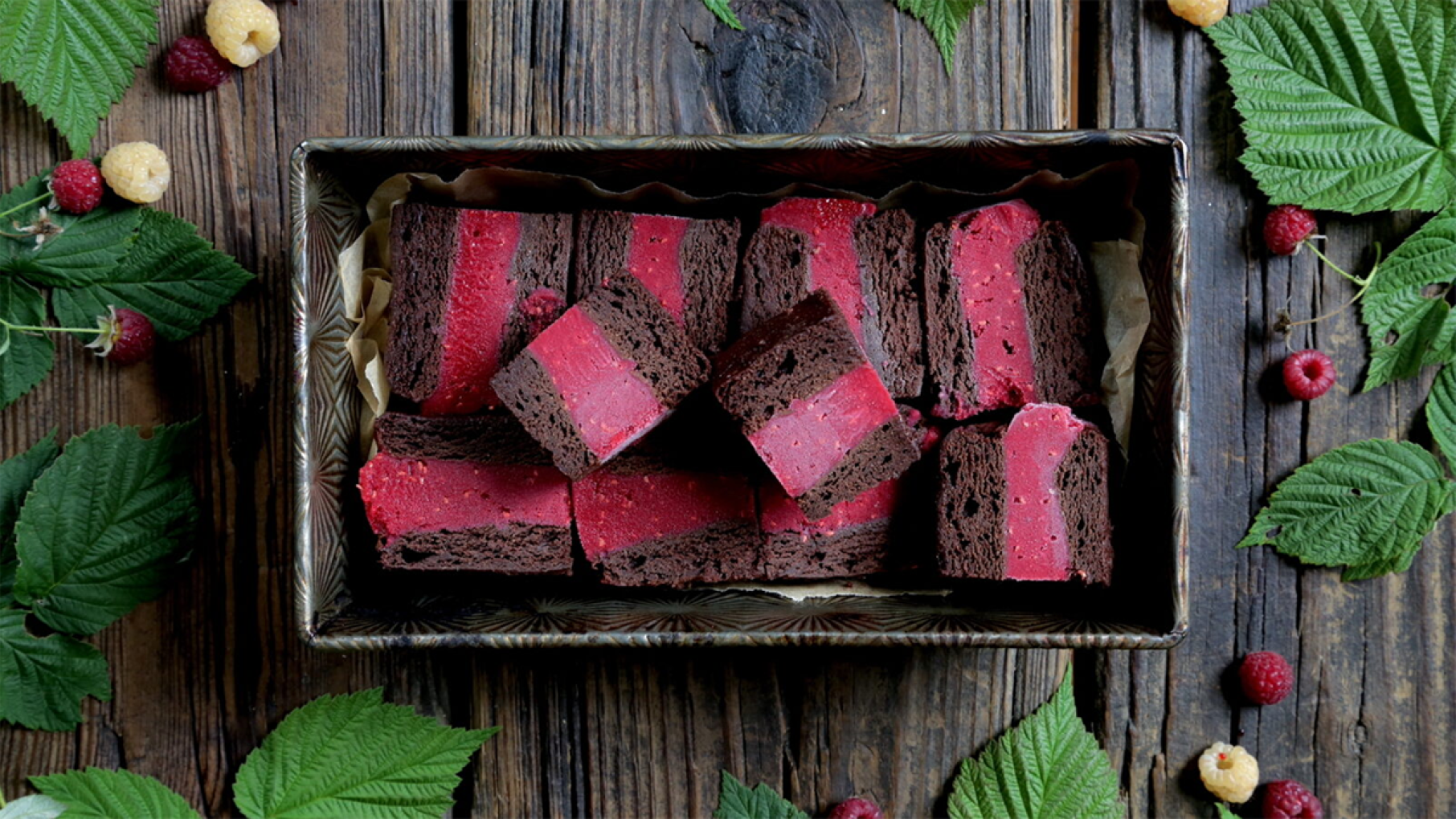 A tray of brownie-raspberry ice cream bars on a table with leaves