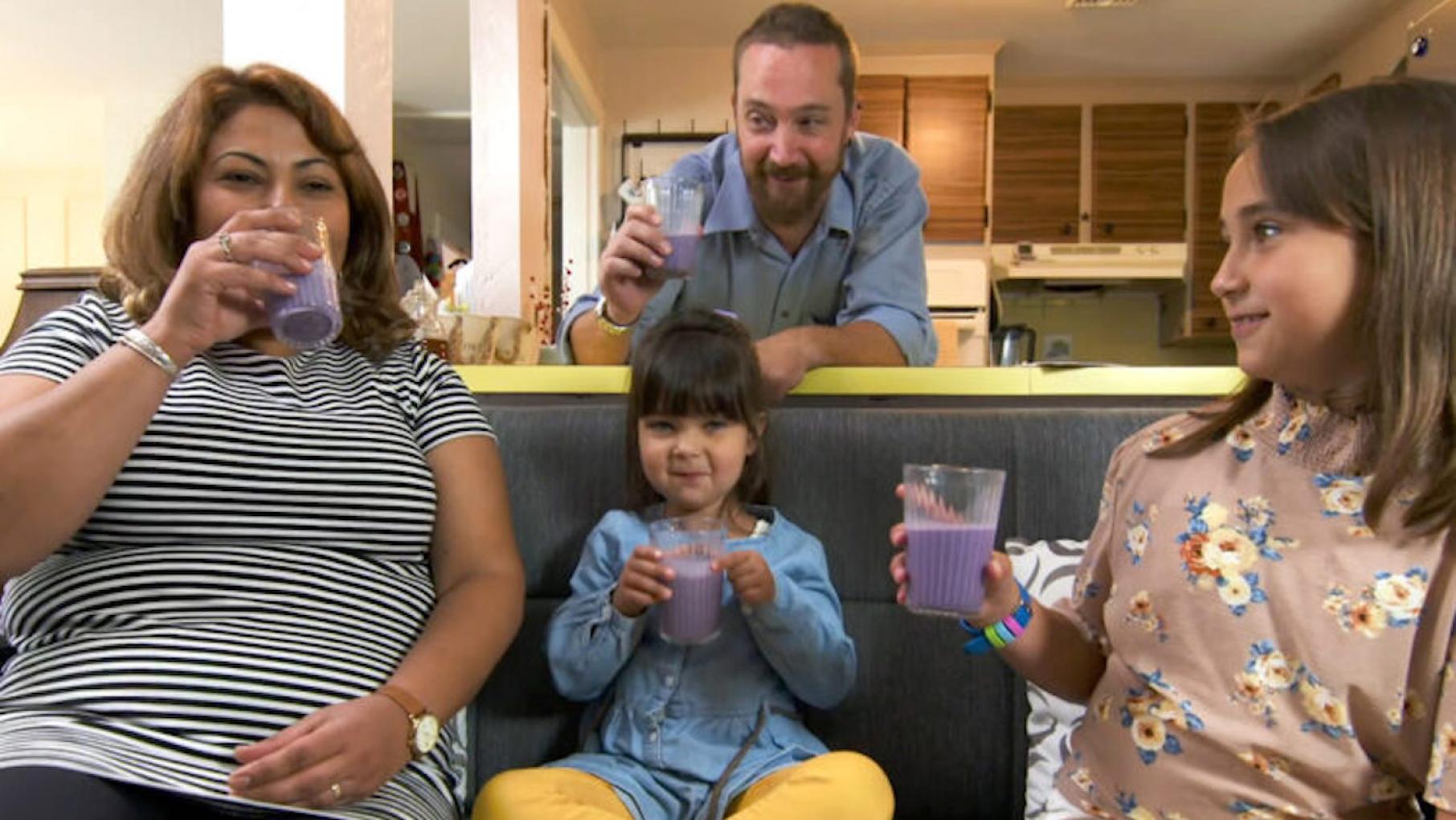A family on a couch enjoys blueberry milk