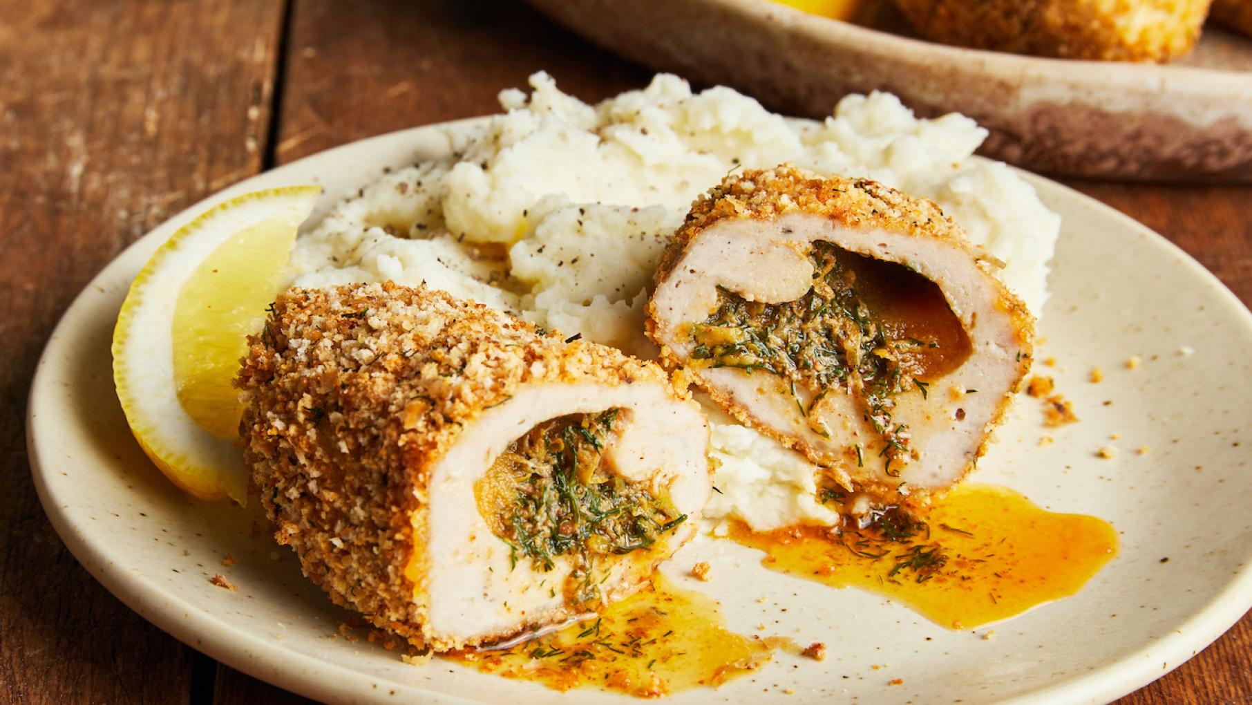 Chicken Kyiv is traditionally made from ground chicken, not a cutlet. Credit: Milk Street Chicken Kyiv cut in half on a plate