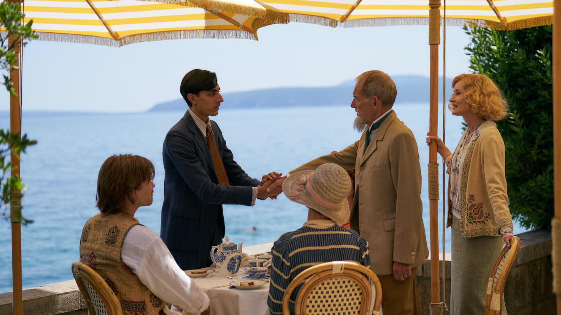 Lucian returns to the hotel with Anish's brother, Virat. Credit: Eagle Eye Drama Virat and George shake hands under umbrellas in front of the sea, with Bella, Lucian, and Amelia watching