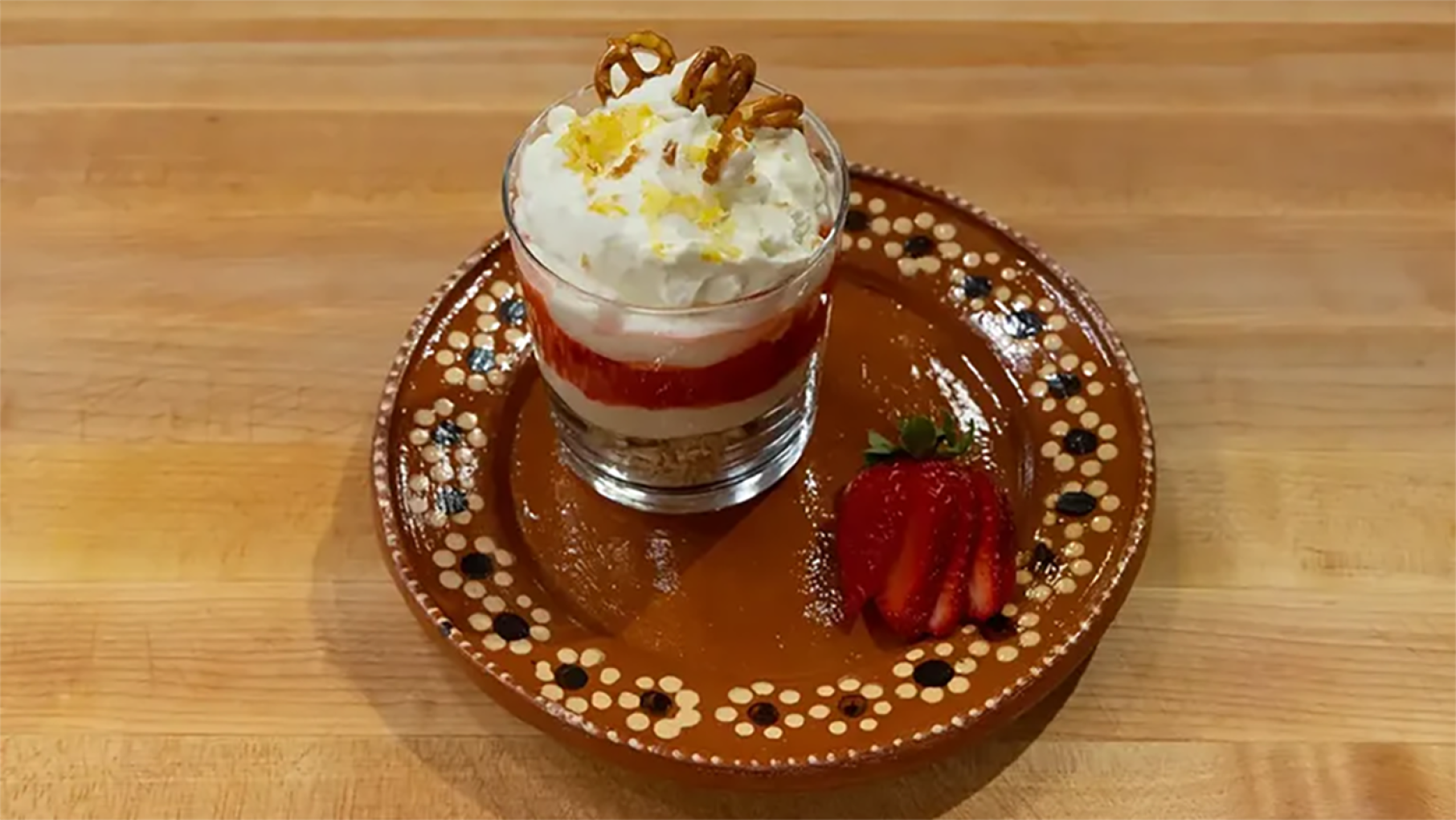 Strawberry pretzel salad is a classic dish worth saving. Credit: PBS A glass cup of a layered dessert on a plate with a sliced strawberry
