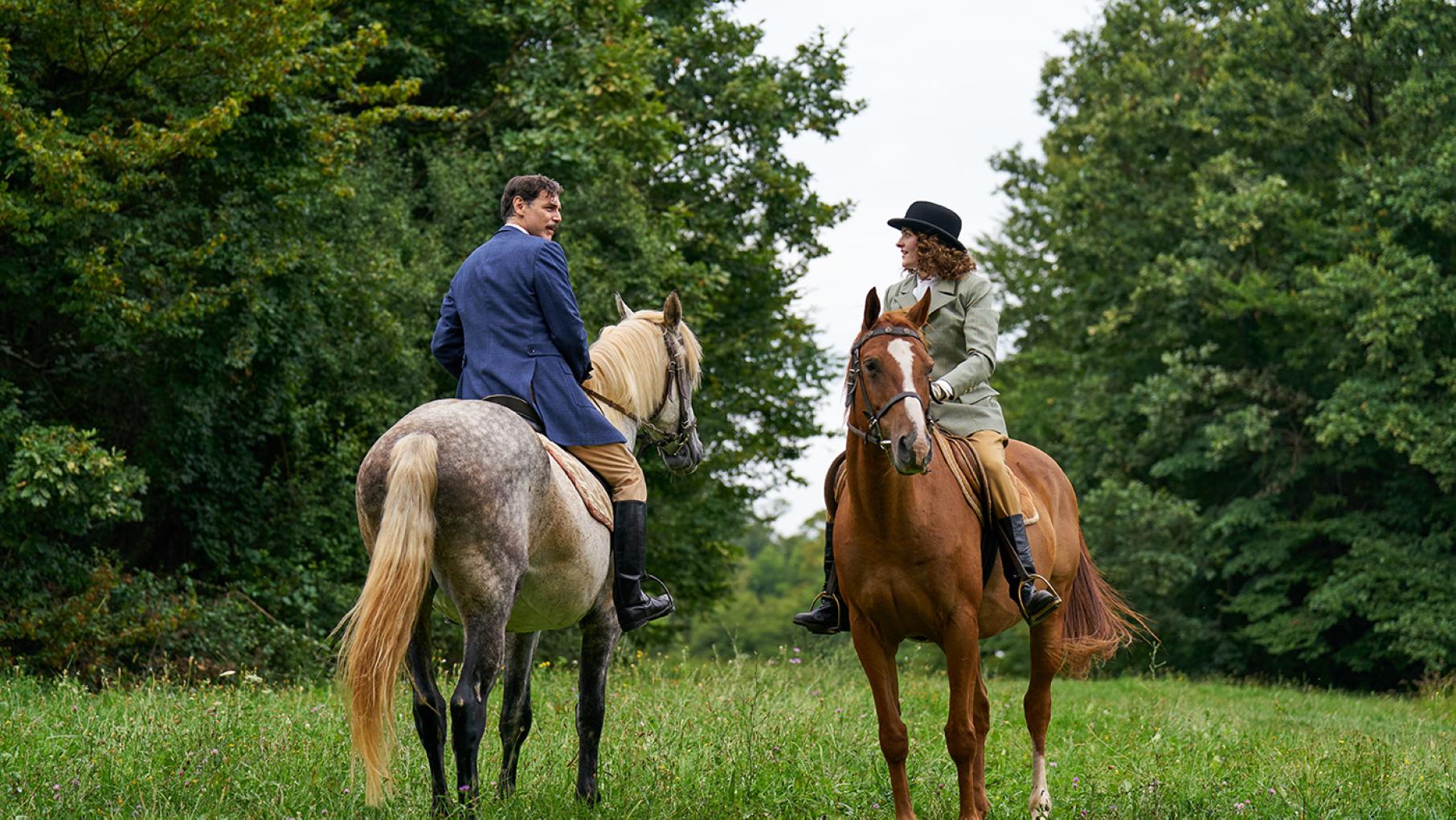 Albani and Alice face each other on horses in a field