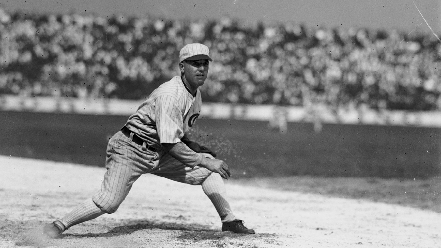 A black and white photo of Eddie Cicotte fielding on a baseball diamond