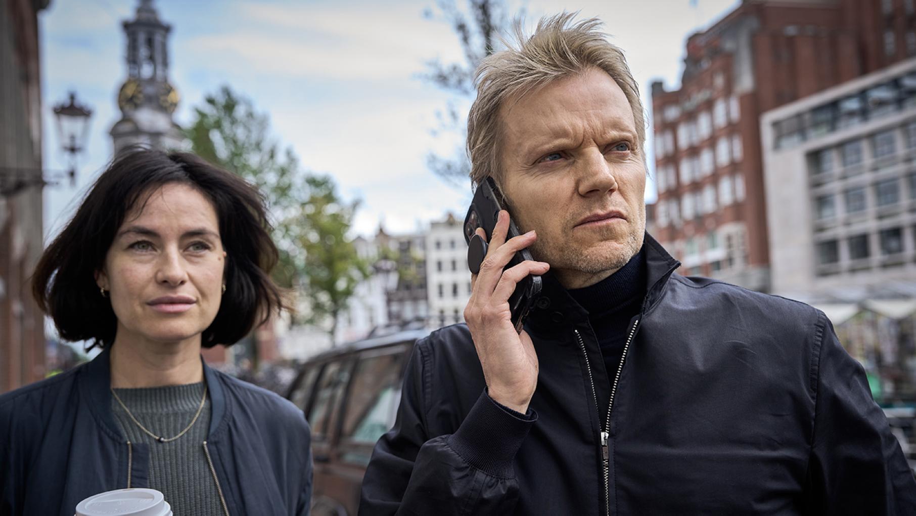 Van der Valk is an old antagonist of the crime lord against whom Gregor Albers was due to testify. Credit: All3Media International and Masterpiece Van der Valk on the phone and Lucienne with a coffee outside