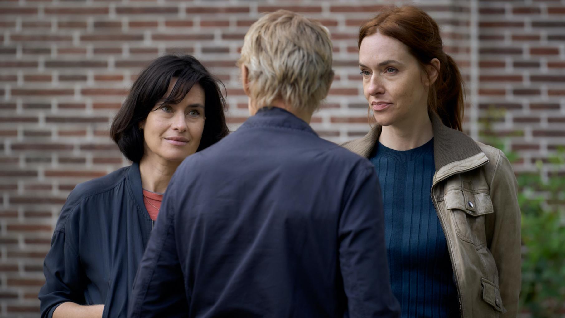 Van der Valk doesn't trust his ex Kalie, thinking she could be involved with the death of a man she was supposed to protect. Credit: All3Media International and Masterpiece Lucienne and Kalie look at Van der Valk, whose back is to the camera