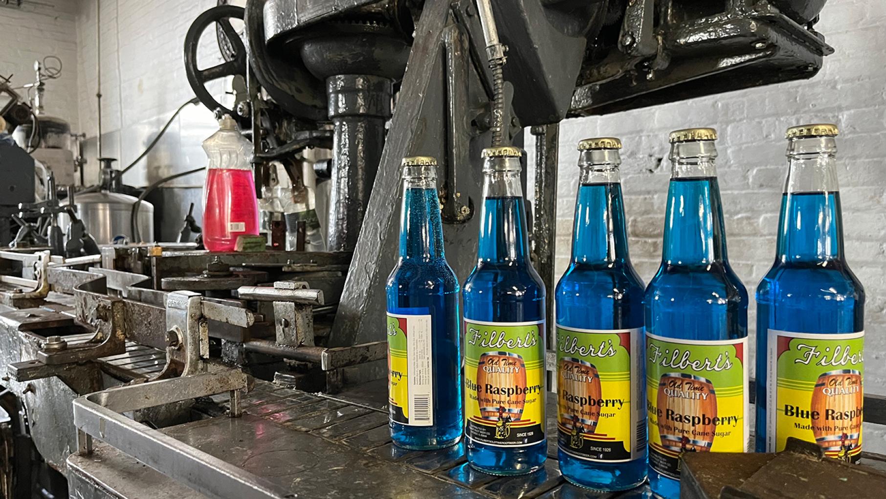Some blue raspberry Filbert's bottles lined up on bottling equipment