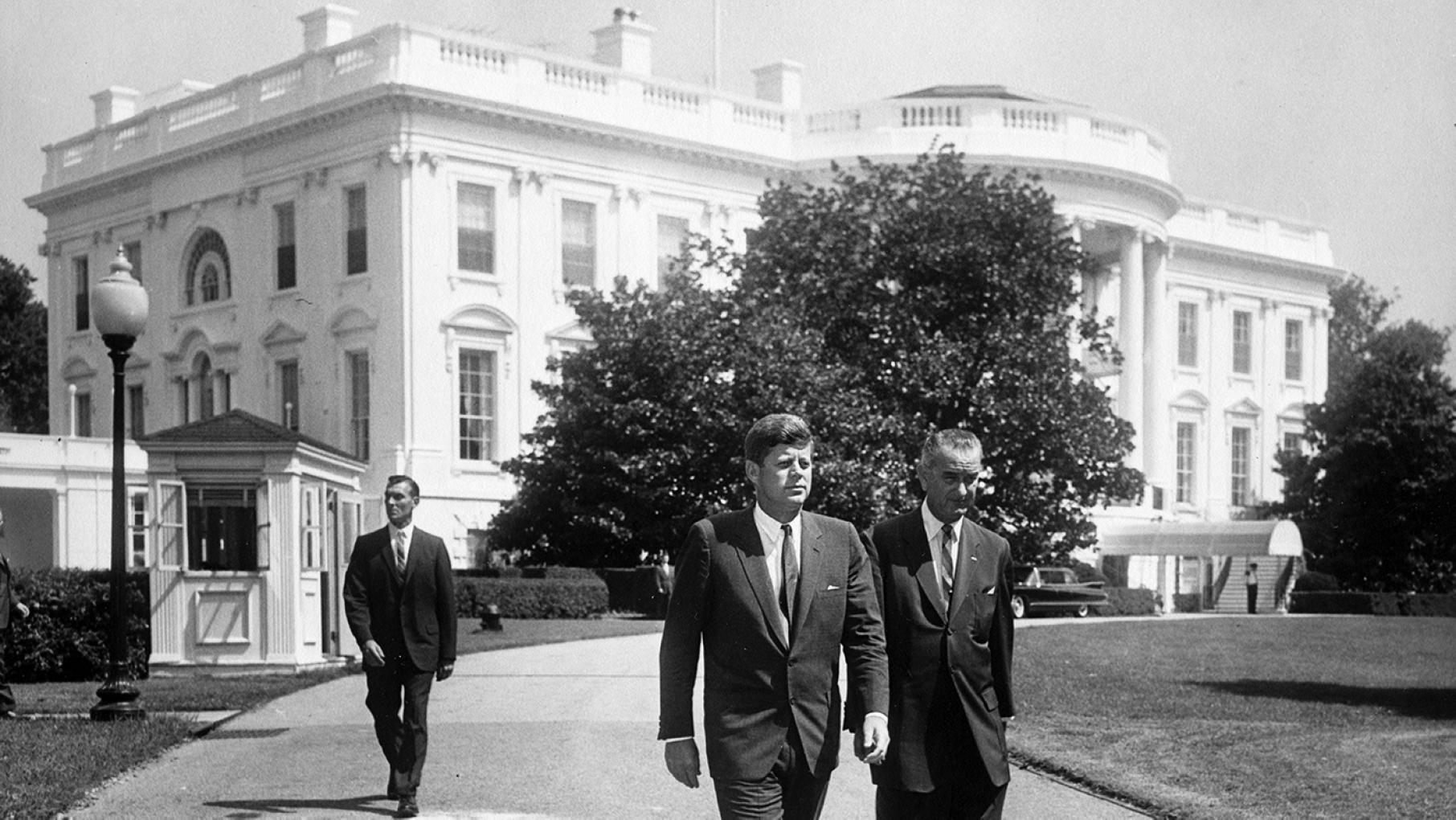 President John F. Kennedy and Vice President Lyndon B. Johnson walking across the South Lawn outside the White House in 1961
