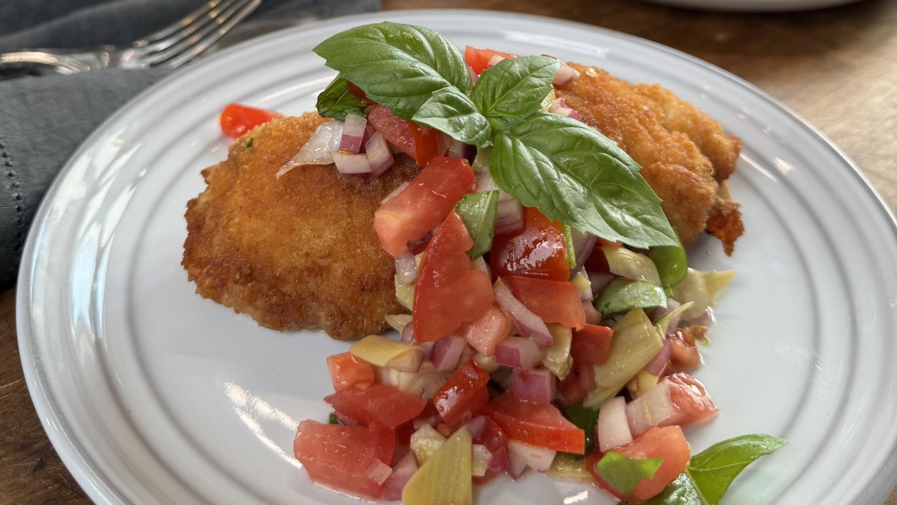 Credit: Lidia's Kitchen A plate with a breaded chicken cutlet topped with tomato salad and basil