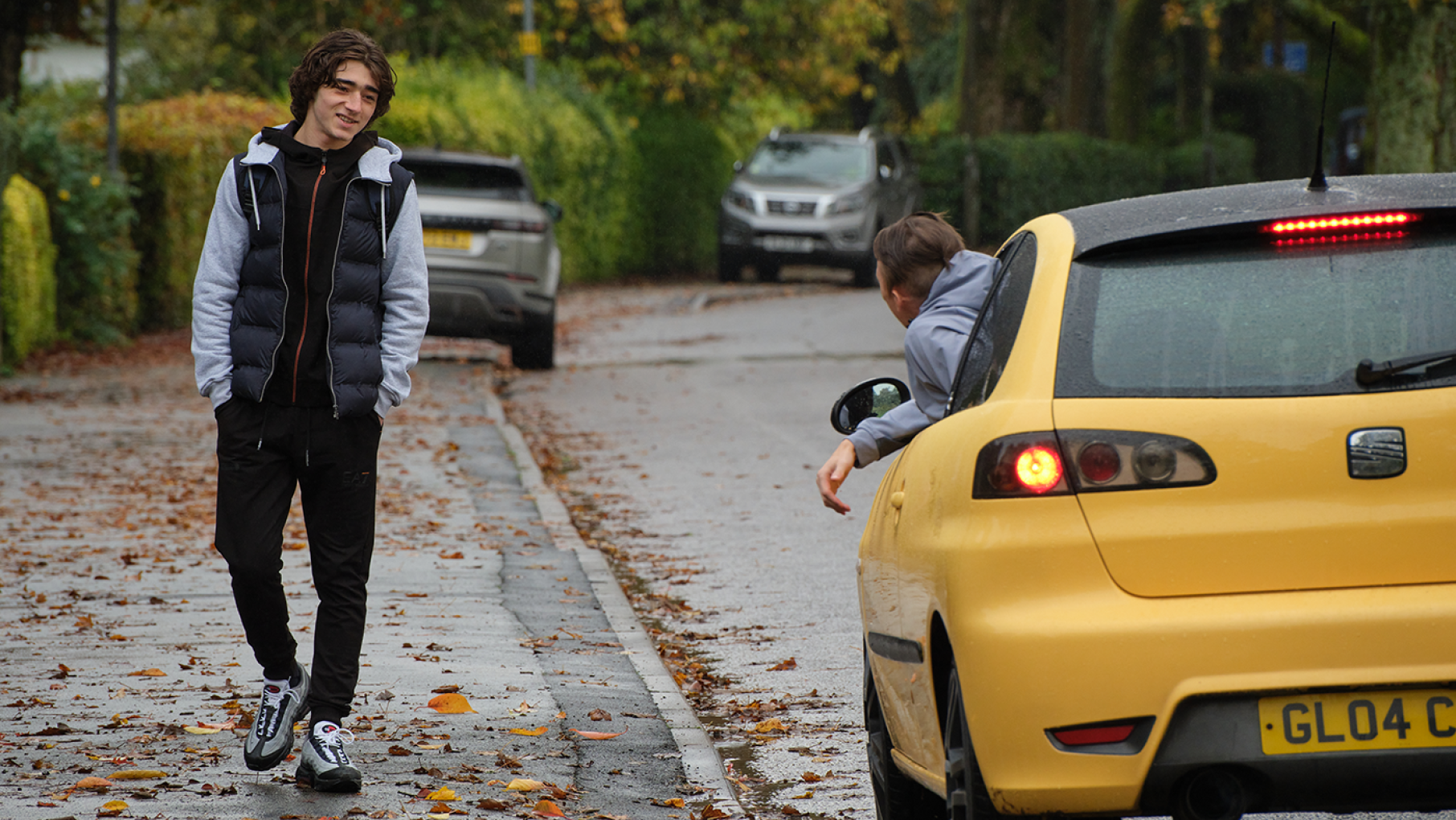 Jack on the street next to a yellow car with a man hanging out the window